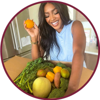 Woman smiling with fresh vegetables and fruit in a kitchen